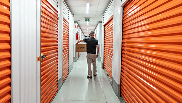 Persona con Scatolone in Mano cammina fra i Corridoi di Maxicubo Self Storage