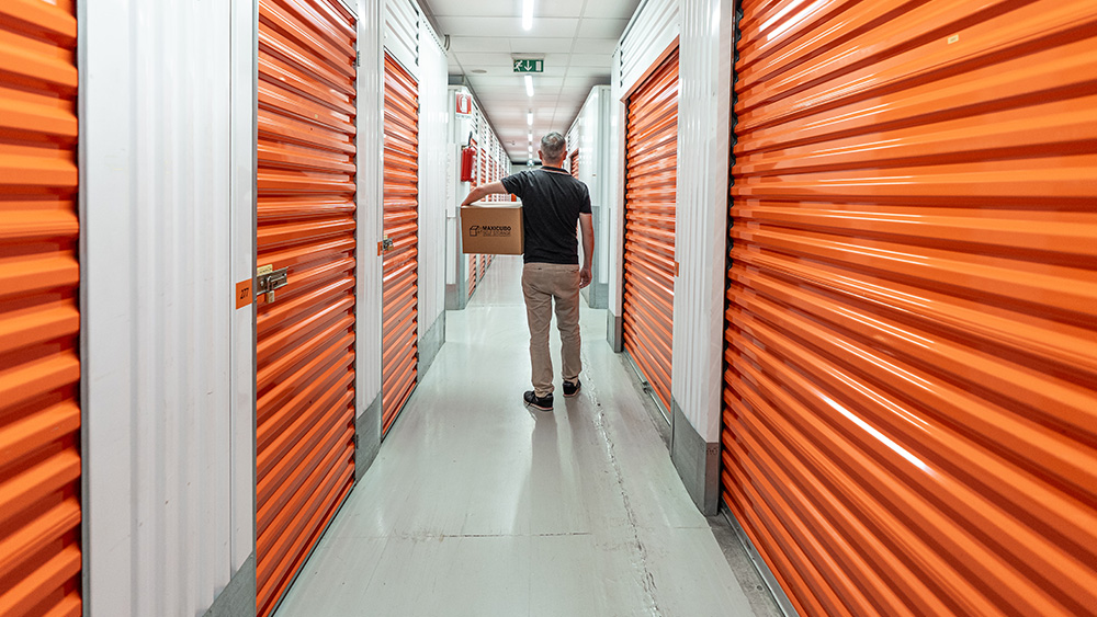 Persona con Scatolone in Mano cammina fra i Corridoi di Maxicubo Self Storage